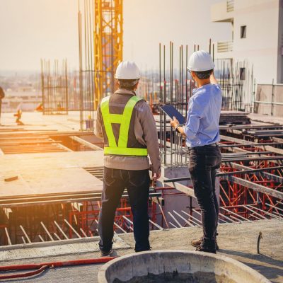 Structural engineer and foreman worker with touch pad discuss, plan working for the outdoors building construction site.